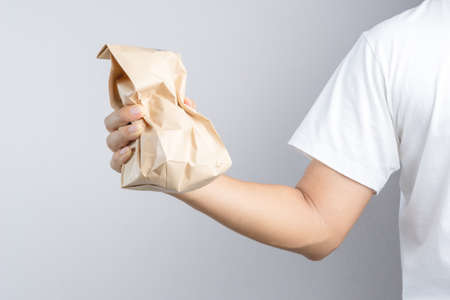 Hand holding crumble brown paper bag on white backgroundのeditorial素材