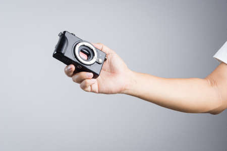 Hand holding mirrorless camera with micro 4/3 sensor  on white backgroundのeditorial素材