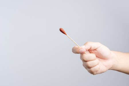Hand holding Povidone iodine swab made of wooden stick and cotton wool for first aid on white backgroundのeditorial素材