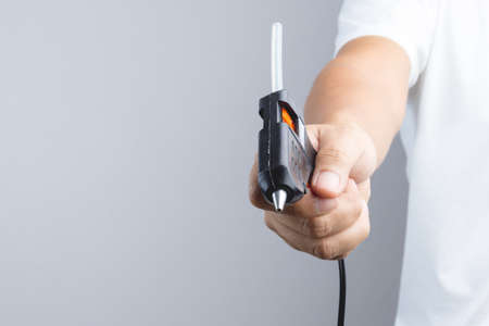 Hand holding electric hot glue gun on white backgroundのeditorial素材