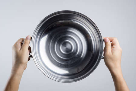 Hand holding stainless steel pan or wide pot on white backgroundのeditorial素材