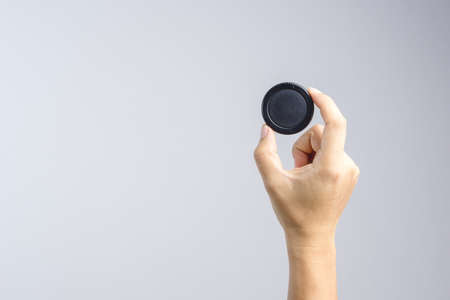 Hand holding lens or camera cap on white backgroundのeditorial素材