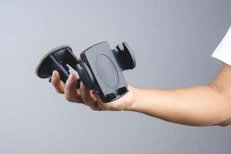 Hand holding phone holder mount for safety use in car on white backgroundのeditorial素材