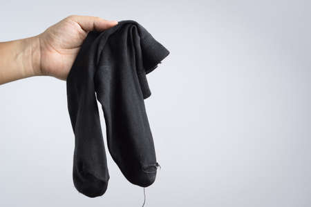 Hand holding pair of used socks on white backgroundのeditorial素材