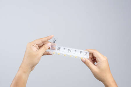 Hand holding plastic weekly pill or medicine box with Braille, the Language of the blind on white backgroundのeditorial素材