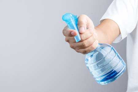 Hand holding blue plastic spray bottle contain pure water on white backgroundのeditorial素材