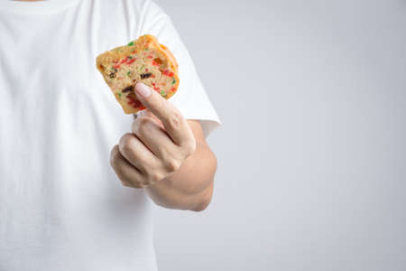 Hand holding traditional fruit cake with raisin, cinnamon and dried cranberries  on white backgroundのeditorial素材