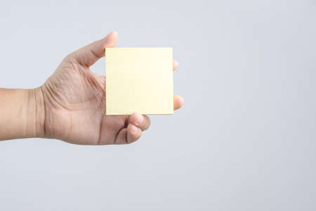 Hand holding sticky post note paper sheet on white backgroundのeditorial素材