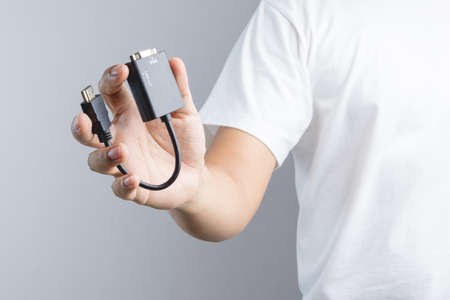 Hand holding adaptor HDMI to VGA cable connector on white backgroundのeditorial素材