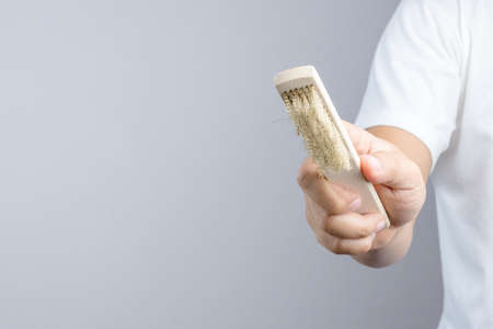 Hand holding small brass brush with wooden handle for cleaning and polishing hard or metal equipment...