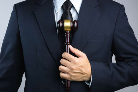 Business man hand holding wooden judge's gavel as a law or justice sign on white backgroundのeditorial素材