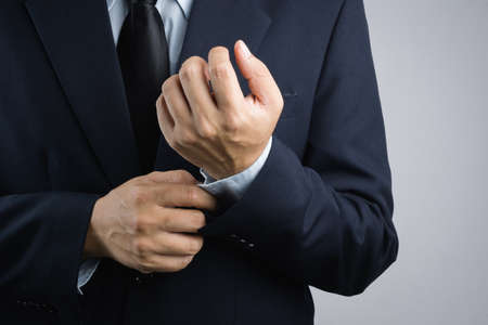 Business man dressing up by adjusting sleeve button on white backgroundのeditorial素材