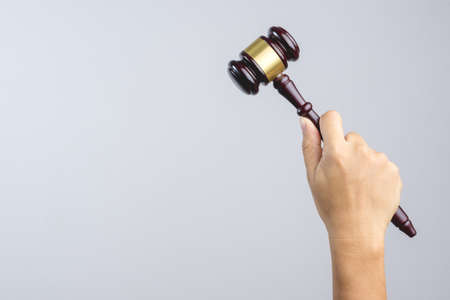 Hand holding wooden judge's gavel as a law or justice sign on white backgroundの写真素材