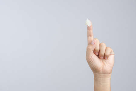 Hand with petroleum jelly on index finger on white background