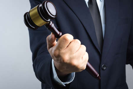 Business man hand holding wooden judge's gavel as a law or justice sign on white backgroundのeditorial素材