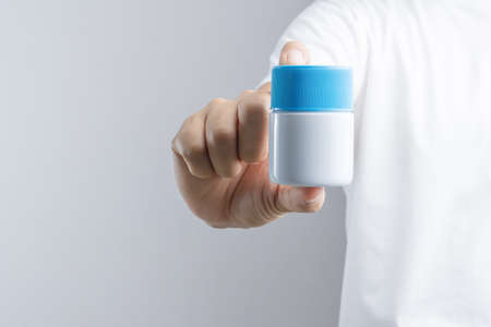 Hand holding cream bottle or petroleum jelly jar for cleaning metal object on white background
