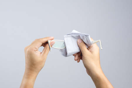 Hand cleaning the lenses of eyesight glasses on white backgroundのeditorial素材