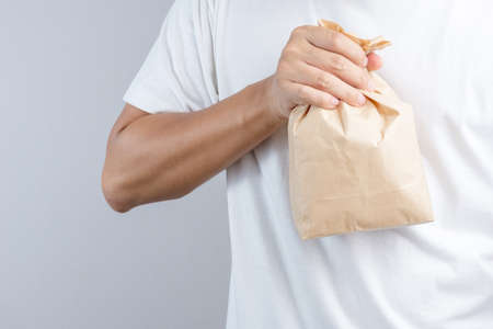 Hand holding crumble brown paper bag panic as a tool for relieving panic attack or being nauseated as Hyperventilation syndrome on white backgroundのeditorial素材