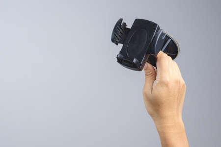 Hand holding phone holder mount for safety use in car on white background