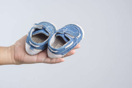 Hand holding old and torn baby shoes as a symbol for precious memory on white background