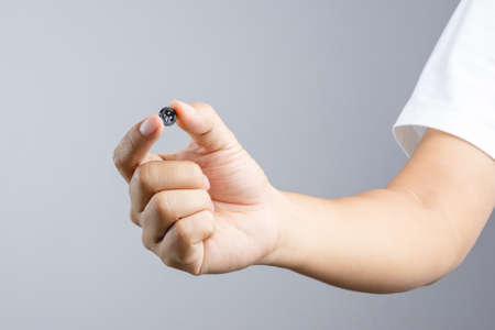 Hand holding black clothing button on white backgroundのeditorial素材