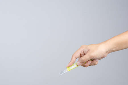 Hand holding office yellow paper cutter on white backgroundのeditorial素材