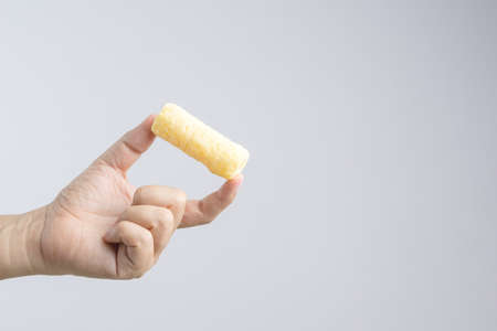 Hand holding yellow crunchy snack made from sweet corn on white backgroundのeditorial素材