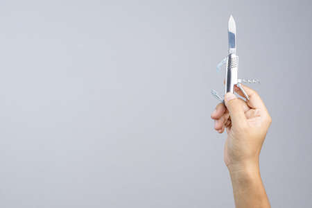 Hand holding silver folding Swiss  army knife, pocket universal tools for multi functions on white backgroundのeditorial素材