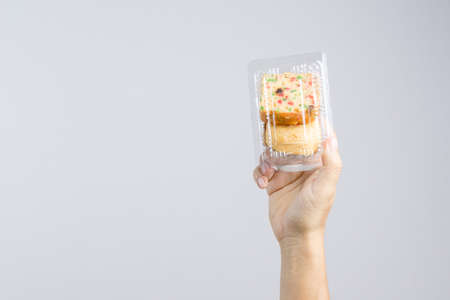 Hand holding traditional fruit cake with raisin, cinnamon and dried cranberries  packed with baked bun on white backgroundのeditorial素材