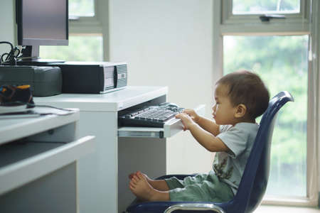 A year and three months old Asian baby trying to use desktop computerのeditorial素材