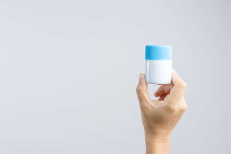 Hand holding cream bottle or petroleum jelly jar for cleaning metal object on white backgroundのeditorial素材