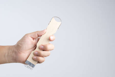 Hand holding zest with wooden handle, tool for peeling fruits and vegetables on white background