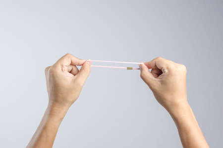 Hand holding pink elastic hair rubber band on white backgroundの写真素材