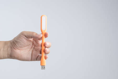 Hand holding plastic USB LED portable lamp on white backgroundの写真素材