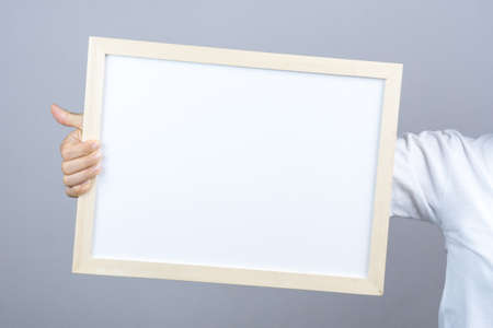 Woman hand holding blank wooden frame on grey backgroundの写真素材