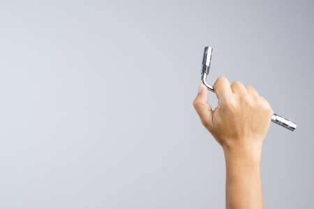 Hand holding metallic cap or ring wrench on white backgroundの写真素材