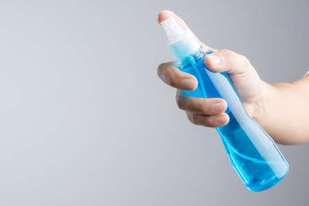 Hand holding plastic spray bottle with blue cleaning liquid normally contain mirror glass cleaner or alcohol on white backgroundの写真素材