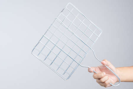 Hand holding portable barbecue grill grid made of steel on white backgroundの写真素材