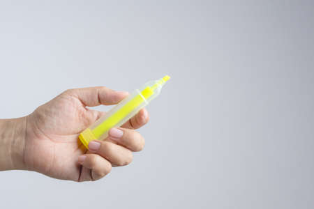 Hand holding Yellow highlighter for writing a color word marker on white backgroundの写真素材