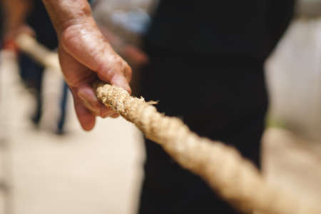 Hand holding big rope for leading people and dead body carrying car to crematory or graveyard as a  Buddhism or a sign of dedication of merit to the departed in Thailandの写真素材