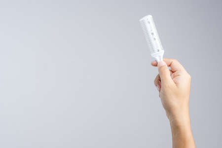 Hand holding comb knife cut tool with blade for slicing hair or adjust hairstyle on white backgroundの写真素材