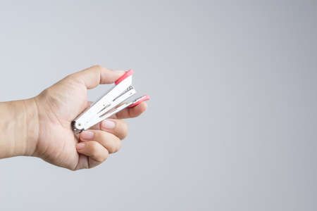 Hand holding stapler, an office supplies for  stapling pages of paper or similar material on white backgroundの写真素材