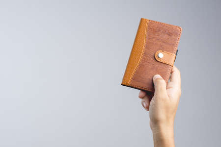 Hand holding vintage brown cover paper notebook on white backgroundの写真素材
