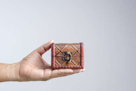 Hand holding small leather treasure chest box on white backgroundの写真素材