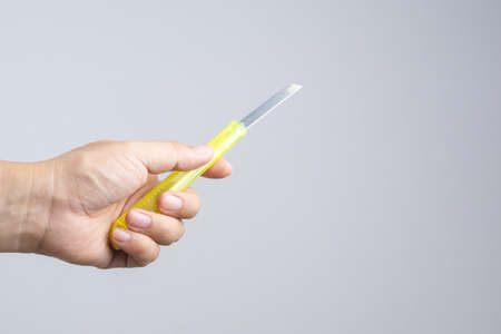 Hand holding office yellow paper cutter on white backgroundの写真素材