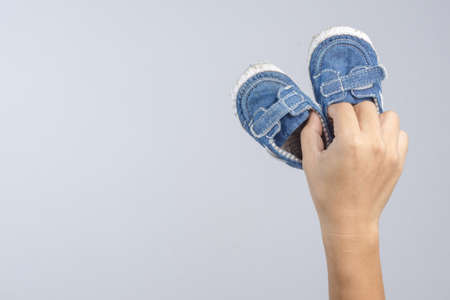 Hand holding old and torn baby shoes as a symbol for precious memory on white backgroundの写真素材