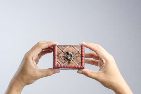 Hand holding small leather treasure chest box on white backgroundの写真素材