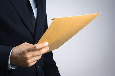 Business man hand holding a self sealing brown envelope document on white backgroundの写真素材