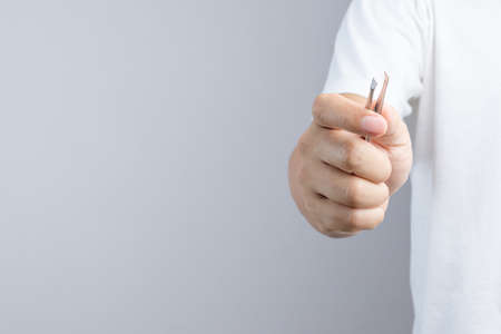 Hand holding metallic tweezers for picking up some small thing or plucking hairs or an eyebrow on white backgroundの写真素材