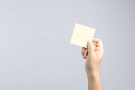 Hand holding sticky post note paper sheet on white backgroundの写真素材